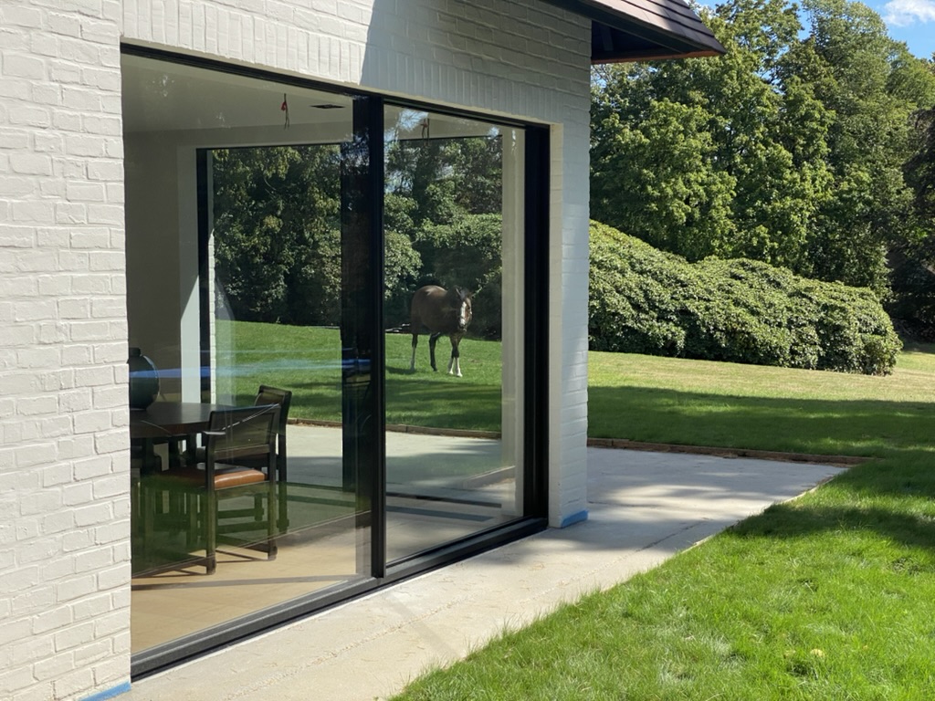 Baie vitrée ouverte sur le jardin avec un cheval à Rhode-Saint-Genèse